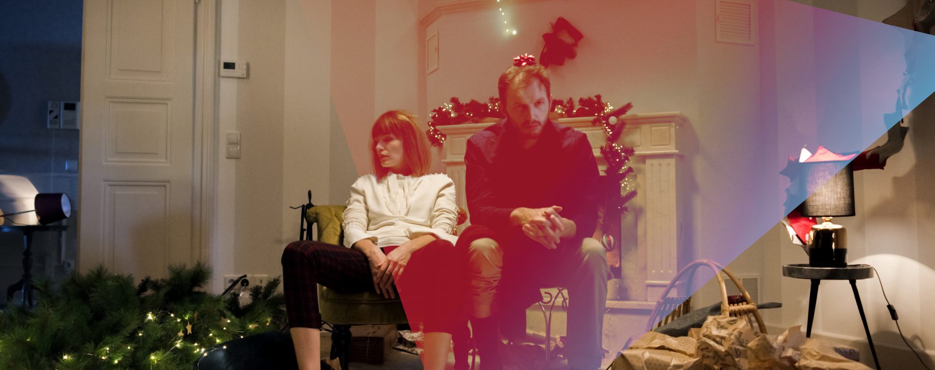 Zwei Personen, die in einem weihnachtlich geschmückten Raum auf Stühlen sitzen